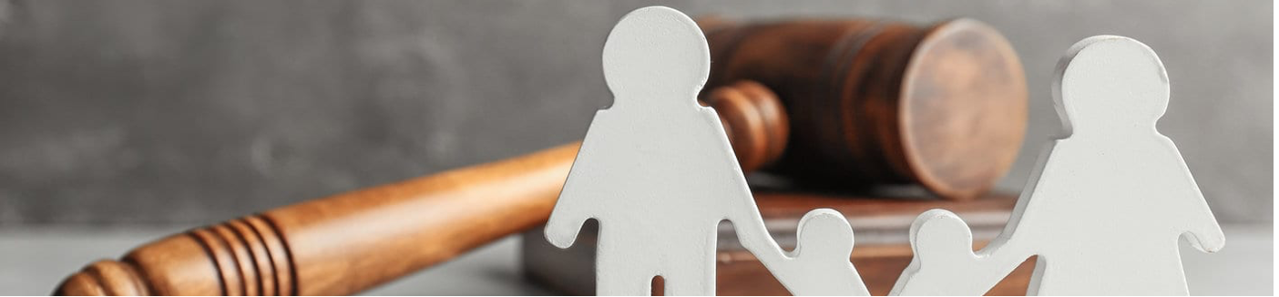 a gavel rests on a table behind a paper cutout family with two partners and two children all holding hands